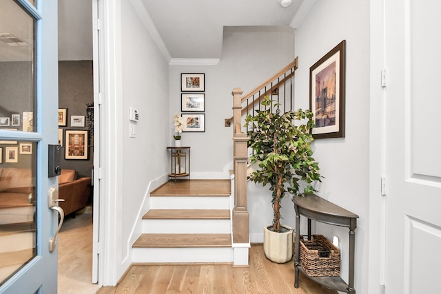 stairs featuring hardwood / wood-style floors and crown molding