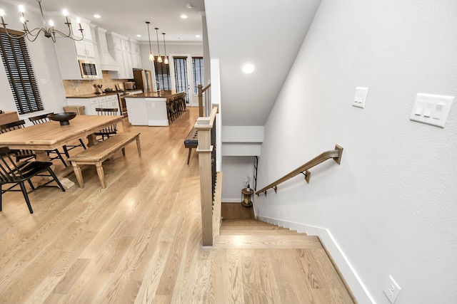 stairs featuring a chandelier and wood-type flooring