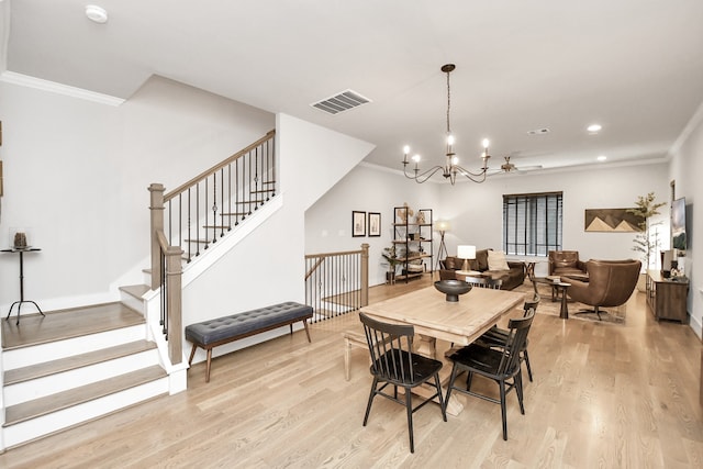 dining space with light hardwood / wood-style flooring, an inviting chandelier, and ornamental molding