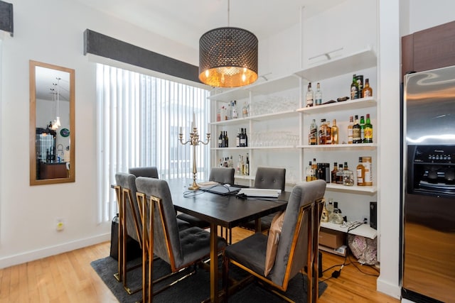 dining area with light hardwood / wood-style flooring and a notable chandelier