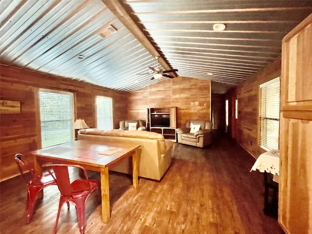 living room featuring lofted ceiling with beams, hardwood / wood-style flooring, ceiling fan, and wood walls