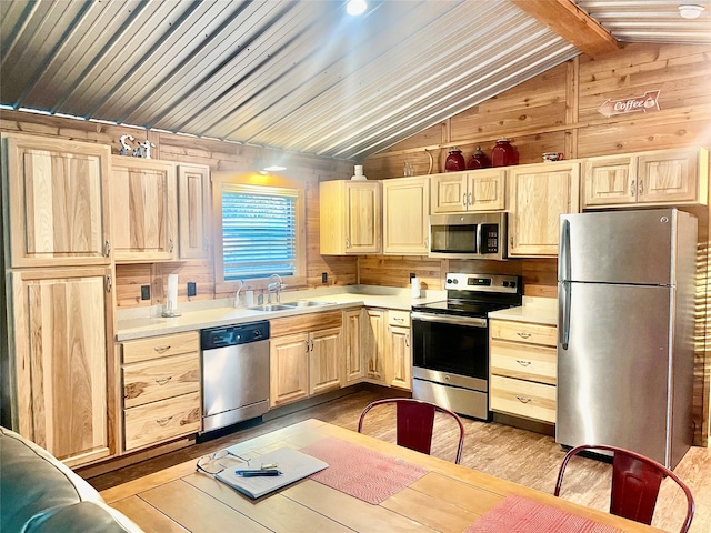 kitchen with vaulted ceiling with beams, wood walls, sink, and stainless steel appliances