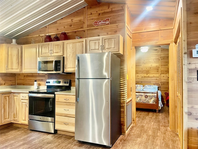 kitchen featuring light hardwood / wood-style floors, wood walls, lofted ceiling, and stainless steel appliances