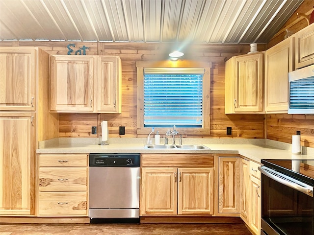 kitchen featuring light brown cabinetry, stainless steel appliances, sink, hardwood / wood-style flooring, and wood walls