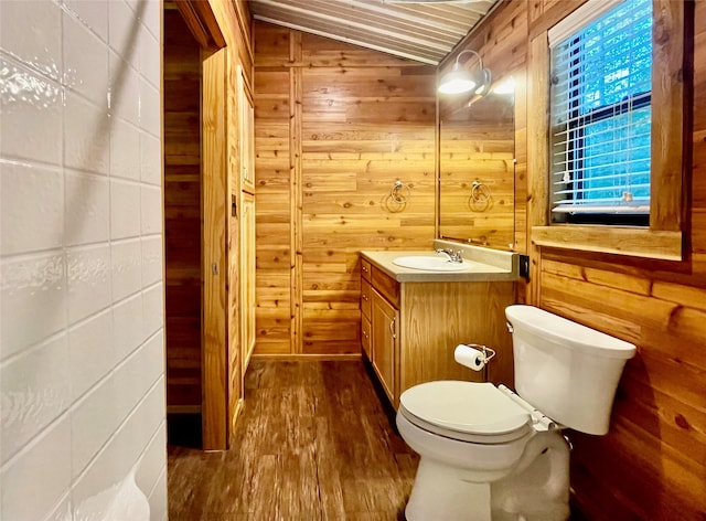 bathroom with wood walls, toilet, vaulted ceiling, and hardwood / wood-style flooring