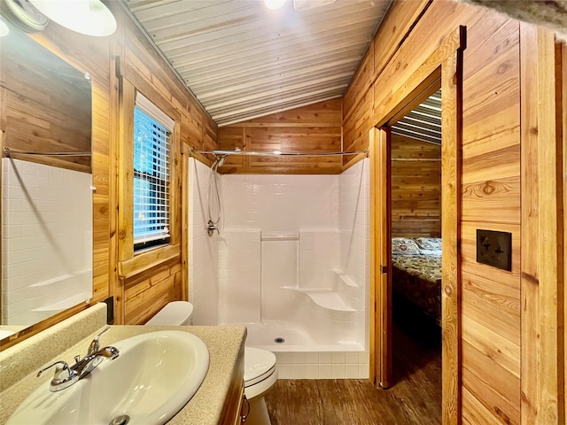 bathroom with a shower, hardwood / wood-style floors, vaulted ceiling, and wood walls