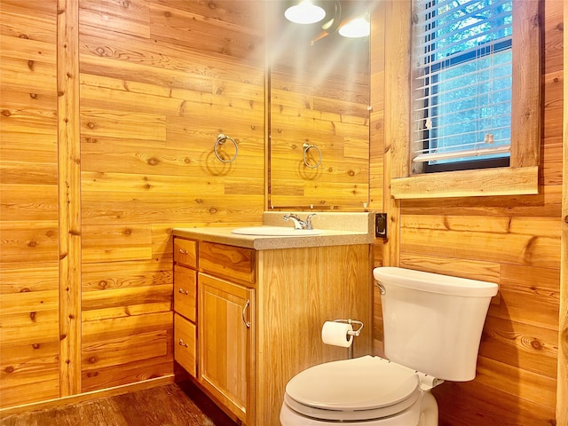 bathroom with wood-type flooring, vanity, toilet, and wooden walls