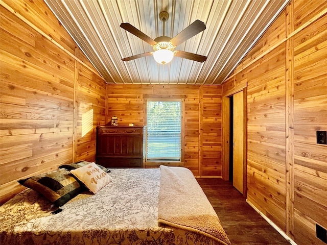 bedroom featuring dark hardwood / wood-style flooring, wooden walls, and vaulted ceiling