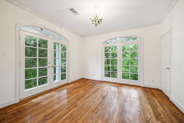 unfurnished room with a healthy amount of sunlight, wood-type flooring, crown molding, and french doors