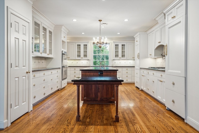 kitchen with white cabinets, a kitchen island, hanging light fixtures, and light hardwood / wood-style floors