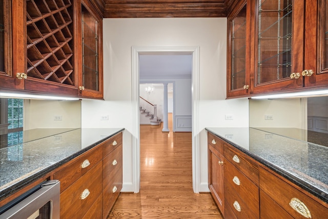 kitchen with ornamental molding, light hardwood / wood-style floors, wine cooler, and dark stone counters