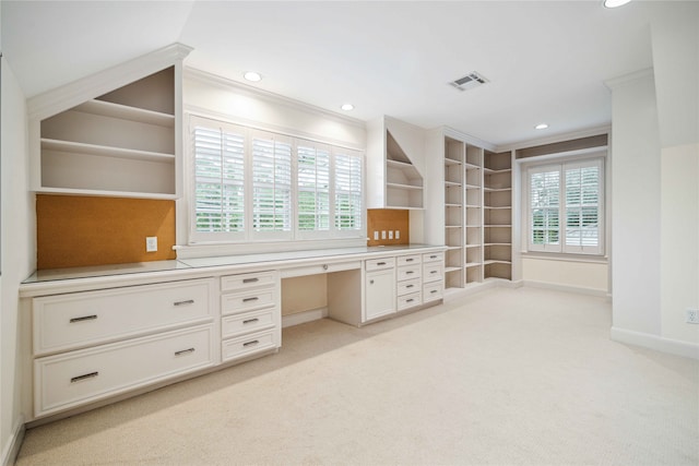 unfurnished office featuring light colored carpet, built in desk, and ornamental molding