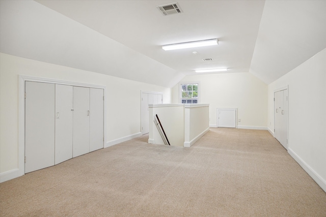 additional living space featuring light carpet and vaulted ceiling