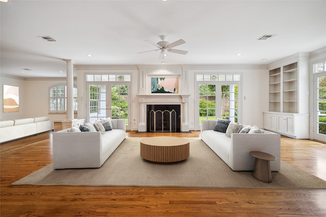 living room featuring crown molding, a wealth of natural light, and light hardwood / wood-style flooring