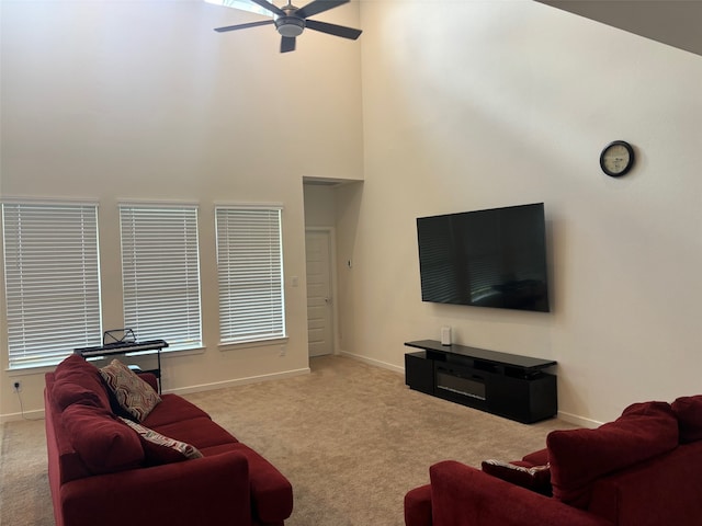 living room featuring a towering ceiling, light colored carpet, plenty of natural light, and ceiling fan