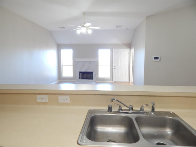 kitchen with sink, ceiling fan, vaulted ceiling, and a high end fireplace