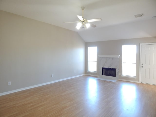 unfurnished living room featuring lofted ceiling, a high end fireplace, ceiling fan, and light hardwood / wood-style floors