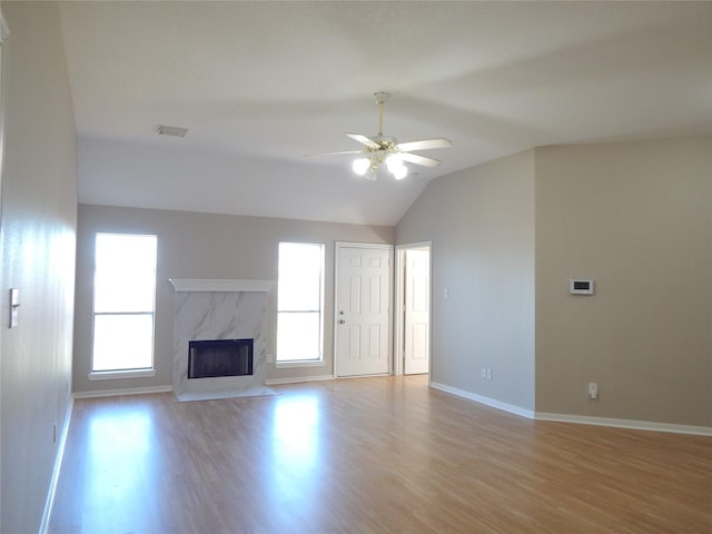 unfurnished living room featuring ceiling fan, plenty of natural light, vaulted ceiling, and a fireplace