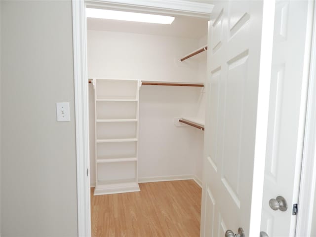 walk in closet with light hardwood / wood-style floors