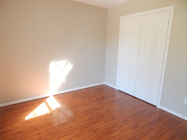 unfurnished bedroom featuring a closet and dark wood-type flooring