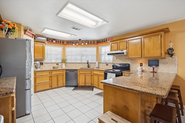 kitchen with kitchen peninsula, appliances with stainless steel finishes, tasteful backsplash, sink, and light tile patterned flooring