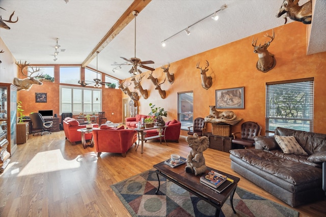 living room with ceiling fan, beamed ceiling, high vaulted ceiling, light hardwood / wood-style floors, and a textured ceiling