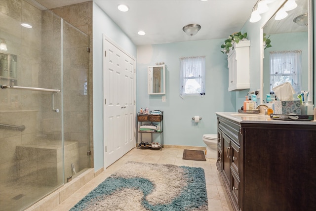 bathroom featuring tile patterned flooring, vanity, toilet, and a shower with door