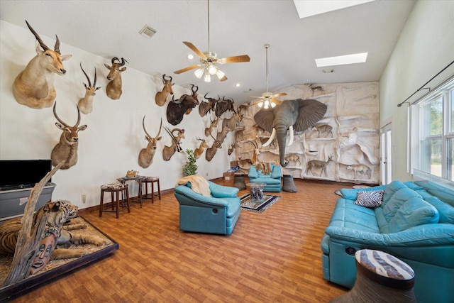 living room featuring hardwood / wood-style floors, ceiling fan, and vaulted ceiling with skylight