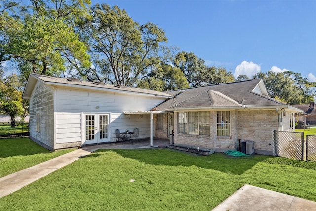 back of property with a yard, a patio area, and french doors