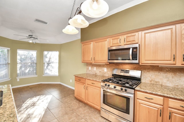 kitchen with appliances with stainless steel finishes, backsplash, light brown cabinetry, light tile patterned floors, and decorative light fixtures