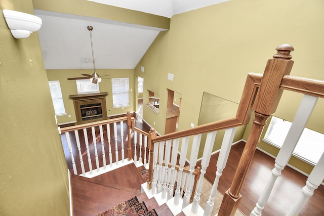 stairs featuring hardwood / wood-style floors, ceiling fan, high vaulted ceiling, and a wealth of natural light