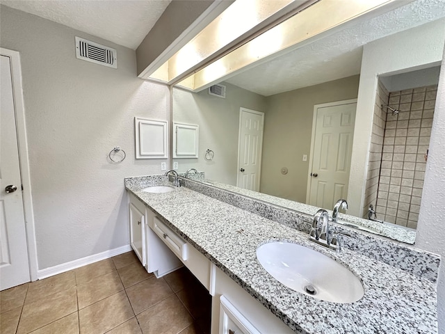 bathroom with a textured ceiling, vanity, and tile patterned floors