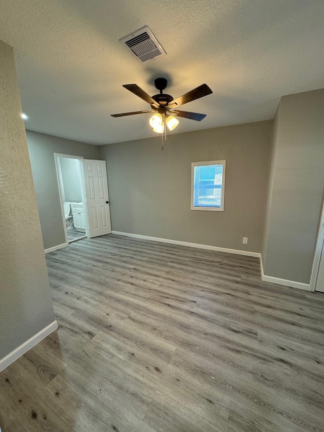 unfurnished room with ceiling fan, light wood-type flooring, and a textured ceiling