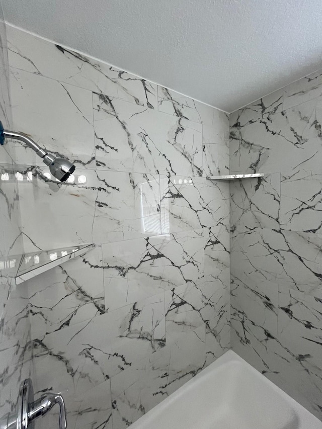 bathroom featuring tiled shower / bath combo and a textured ceiling