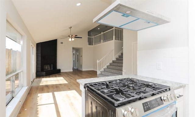 kitchen featuring high vaulted ceiling, light hardwood / wood-style flooring, plenty of natural light, and stainless steel range with gas stovetop