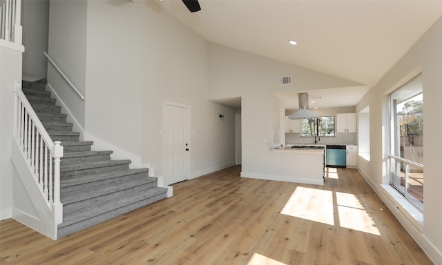 unfurnished living room featuring light hardwood / wood-style floors, high vaulted ceiling, and sink