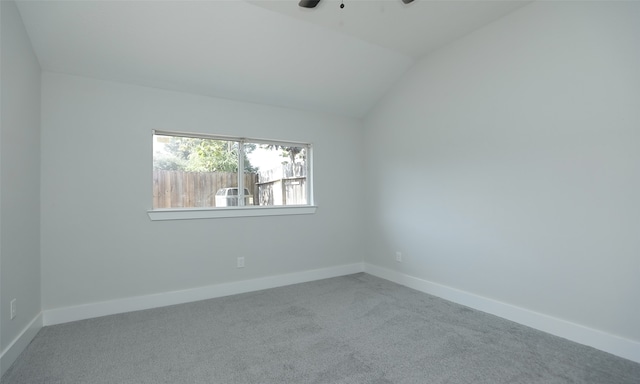 carpeted spare room featuring vaulted ceiling and ceiling fan