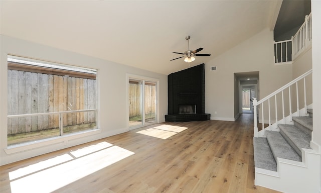 unfurnished living room featuring ceiling fan, wood-type flooring, high vaulted ceiling, and a brick fireplace