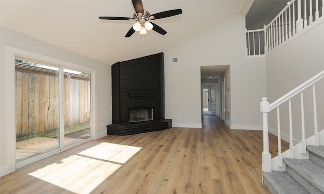 living room featuring high vaulted ceiling, hardwood / wood-style flooring, a brick fireplace, and ceiling fan