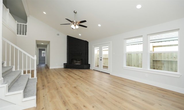 unfurnished living room with a brick fireplace, ceiling fan, high vaulted ceiling, and light hardwood / wood-style flooring