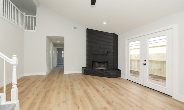 unfurnished living room with french doors, a fireplace, light hardwood / wood-style flooring, and vaulted ceiling