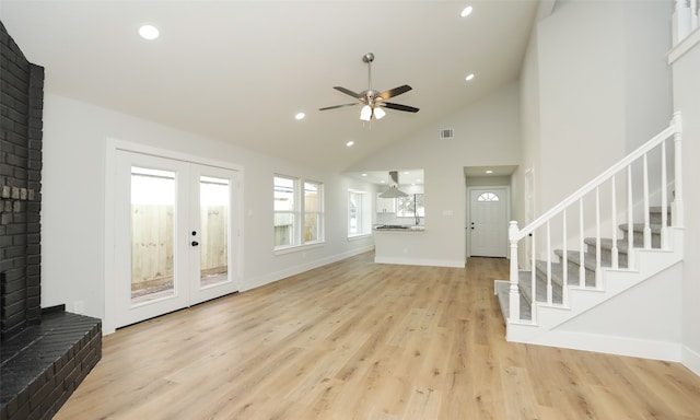 living room with high vaulted ceiling, french doors, a brick fireplace, light hardwood / wood-style flooring, and ceiling fan