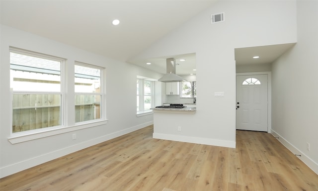 unfurnished living room with plenty of natural light, high vaulted ceiling, and light wood-type flooring