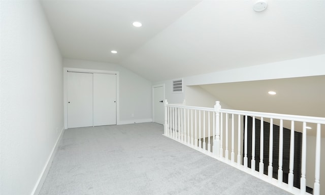 additional living space with light colored carpet and vaulted ceiling