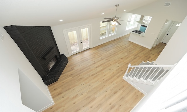 living room featuring a fireplace, french doors, light hardwood / wood-style flooring, and ceiling fan