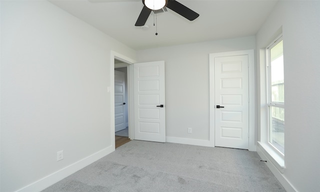 unfurnished bedroom with multiple windows, ceiling fan, and light colored carpet