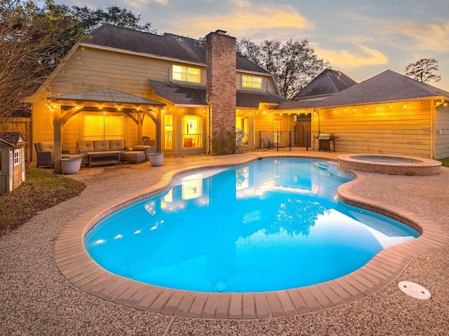 pool at dusk with outdoor lounge area, a gazebo, an in ground hot tub, a grill, and a patio