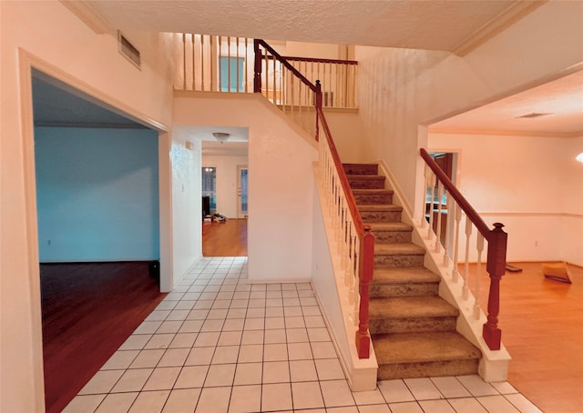 stairs featuring hardwood / wood-style flooring, crown molding, and a textured ceiling