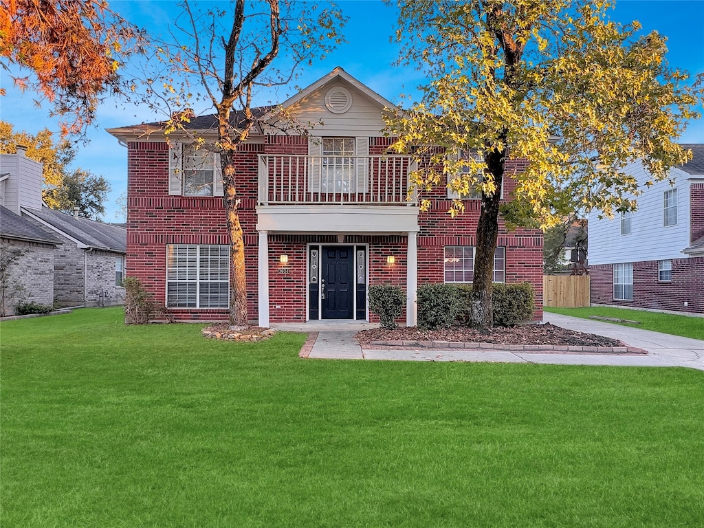 view of front of house featuring a balcony and a front yard