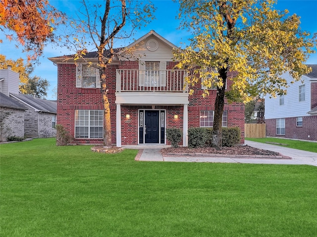 view of front of house featuring a balcony and a front yard